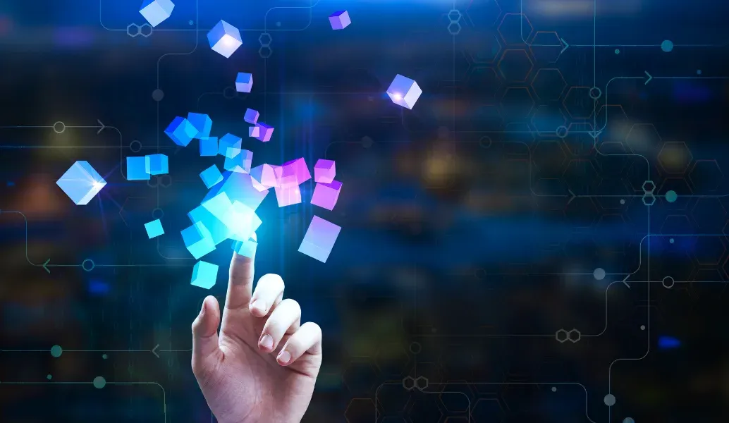 A fingertip touching a cluster of glowing pink and blue cubes rising from a dark circuit-board background.